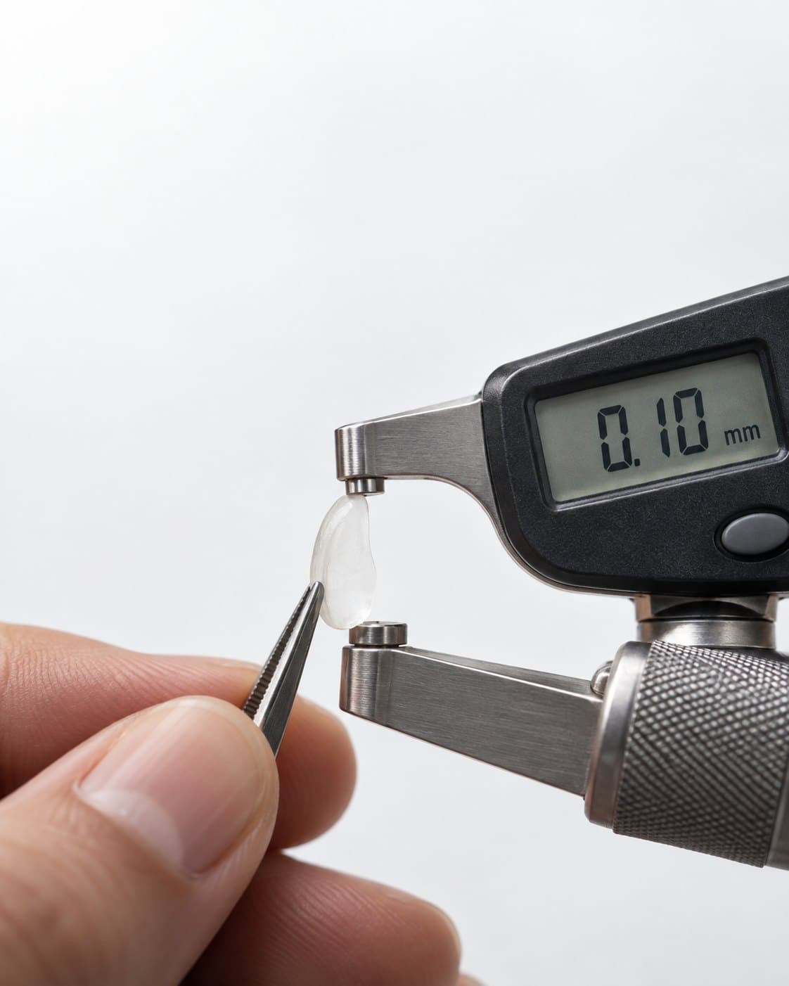 A veneer shell held in a micrometer that reads 0.10 mm