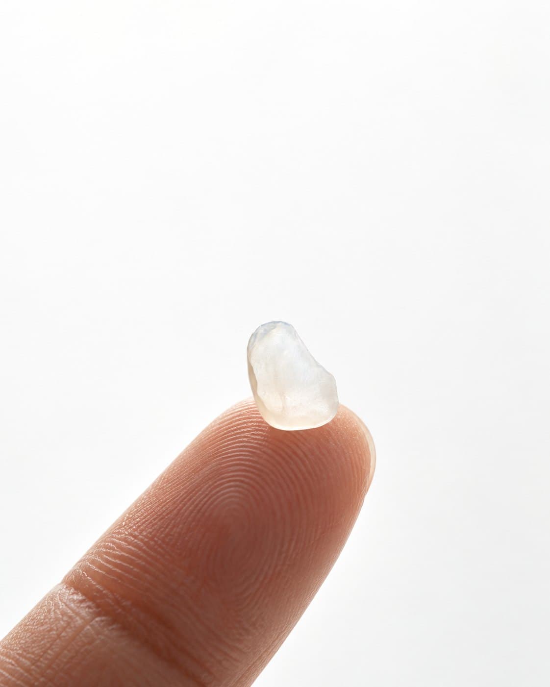 A LUMIS veneer shell resting on a fingertip